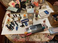 Wide view of the table showing various small bottles, incense oils, and a metal paper cutter on a floral tablecloth.