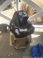 Soft-sided black fabric pet carrier placed on top of the beige plastic hard top pet crate with metal door, showing the two carriers together.