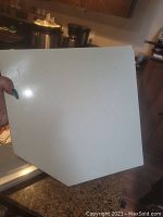 Top view of white metal corner shelf showing flat surface and wear.