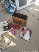 Photo showing the brass-colored magazine holder, magazines, plush panda, serving tray, and pet dish on a concrete floor.