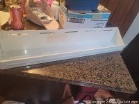 White metal shelf with lip shown on countertop, visible wear and used condition.