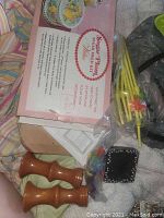 Assorted kitchen and bar items including wooden salt and pepper shakers, boxed floral-themed packaging, and yellow nip straws, taken to show included small items in lot.