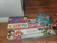 Photo showing Nintendo Monopoly Collector's Edition board game featuring Mario, Luigi, and Wario characters, Scattergories and Charades games, and Game Pad box.
