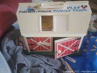 Photo of vintage Fisher Price Play Family Farm toy barn showing closed barn doors, handle on top, and exterior design.