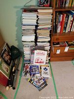 Overall view of tall stacks of sports books and magazines with card albums and loose cards at base