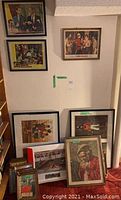 Photo showing several framed prints leaning against a wall, including social and portrait scenes.