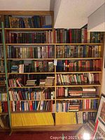 Front view of two wood bookcases filled with hardcover books on multiple shelves