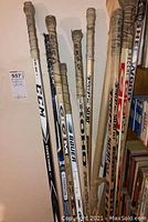 Front view of eight autographed hockey sticks standing upright against a wall