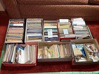 Eight shoeboxes containing postcards and souvenir items displayed on floor