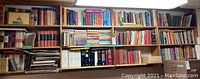 Wide shot showing three full shelves of assorted vintage books of various topics and sizes.