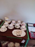 Overview of assorted tea cups and saucers on wooden surface, showing floral and gold detailed china pieces.