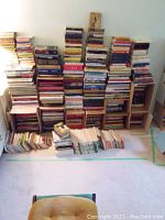 Eight stacks of assorted books on floor against wall
