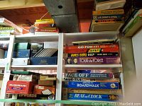 Two shelving units with multiple vintage board games stacked horizontally and vertically. Games include Face Off, James Bond 007, Go For It, Careers, Beat The Clock, Sorry, Balderdash among others.