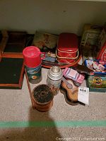 Top view of assorted decorative tins and containers with varied vintage designs and artwork, including a Coca-Cola tin and a ballet dancer tin.