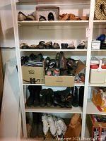 Four shelves with men's and women's shoes including sandals and dress shoes, some in boxes, and boots on top shelf.