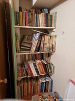 Four shelves filled with a large assortment of children's books of various sizes and thicknesses, standing and stacked horizontally and vertically.