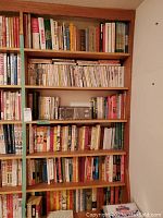 Photo showing a full view of one wooden bookshelf filled with assorted baseball books across eight shelves, arranged vertically and horizontally in some areas.