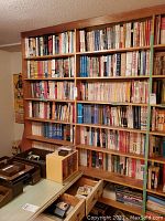 Wide view of wooden bookcase showing multiple shelves filled with hockey books plus drawers below.