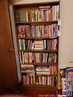 Six-shelf bookcase loaded with various sports-related books