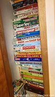 Stack of board game boxes including Disney Spin, Mad games, Charlie's Angels, Bonkers!, Bionic Woman, Super Spy.