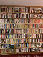 Three oak bookcases each with nine shelves filled with paperback books