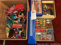 Three boxes and a blue bag containing loose die-cast vehicles and empty blister tray