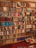 Three full-height wooden bookcases containing books on 27 shelves
