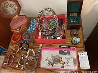 Full view of bracelets, rings, pins, earrings, and jewelry boxes arranged on wooden surface
