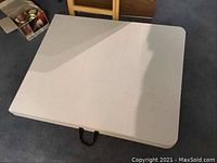 Table folded in half showing smooth resin top surface and carry handle.