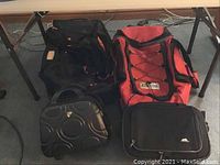 Front view of all four luggage bags arranged on the floor under a table, showing size and color differences