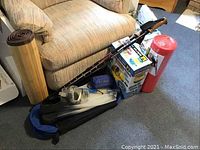 Shows the hydro sling, walking sticks, a box with snorkel gear, flippers, seated cushion and rolled bamboo runner against a couch and floor surface.