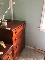 Side angle photo of wood dresser showing top surface and four drawers with round wooden knobs.