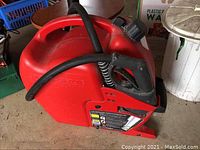 Red plastic 20L G Can refuelling system with attached hose and nozzle, showing ergonomic handle and screw-on cap.