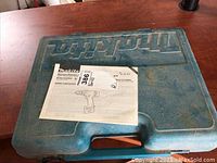 Blue plastic carrying case for Makita drill kit with instruction sheet on top