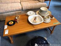 Pine coffee table displayed with various dishes and small items on top to show size and surface area.