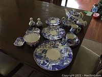 Overview of entire set arranged on dining table showing plates, cups, saucers, salt and pepper, teapot, sugar bowl and creamer