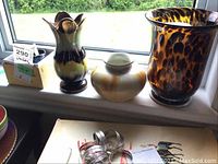 Three vases on a windowsill including tall West German with fluted top, medium beige West German, and tall leopard print glass vase