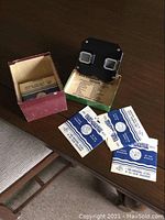 View-Master viewer along with original box and three reels laid out on a wooden table