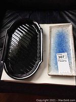 Two platters shown side by side on black surface; black Mikasa platter has scalloped edges and rectangular platter has blue speckled glaze