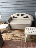 Full view of Rubbermaid resin deck bench with two white patio side tables on wooden deck against grey siding.