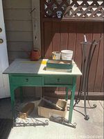 Overview of green potting table, plant stand, garden pots, and assorted garden items grouped together.