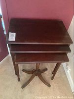 Photo showing three wooden nesting tables with rectangular tops in descending size order, front and angled view.