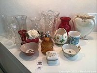 Photo showing collection of various glass, ceramic, and crystal vases and decorative pieces in multiple colors and styles.