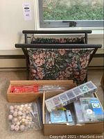 Photo showing floral fabric knitting bag with an open top and two compartments containing various boxes and bags of beads.
