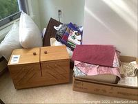 Wooden sewing box with quilting fabrics and box of sewing notions on floor.