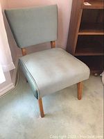Side angle view of the vintage chair showing upholstery and wooden leg design.