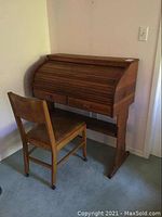 Side angle view of wood roll top desk and wooden chair showing overall condition and dimensions