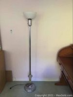 Full view of the vintage floor lamp standing against a wall next to a wooden desk.