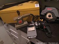 Yellow wooden toolbox with metal latch and handle, corded power drill, and sander on countertop alongside Craftsman circular saw.