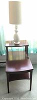 Full view of the wooden end table with lamp placed on top, showing table shape and lamp design